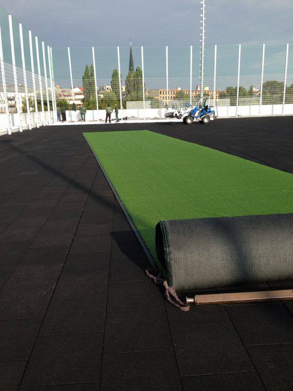 Die stoßdämpfende Schicht ist eingebracht und die erste Rolle Kunstrasen wird ausgerollt ...