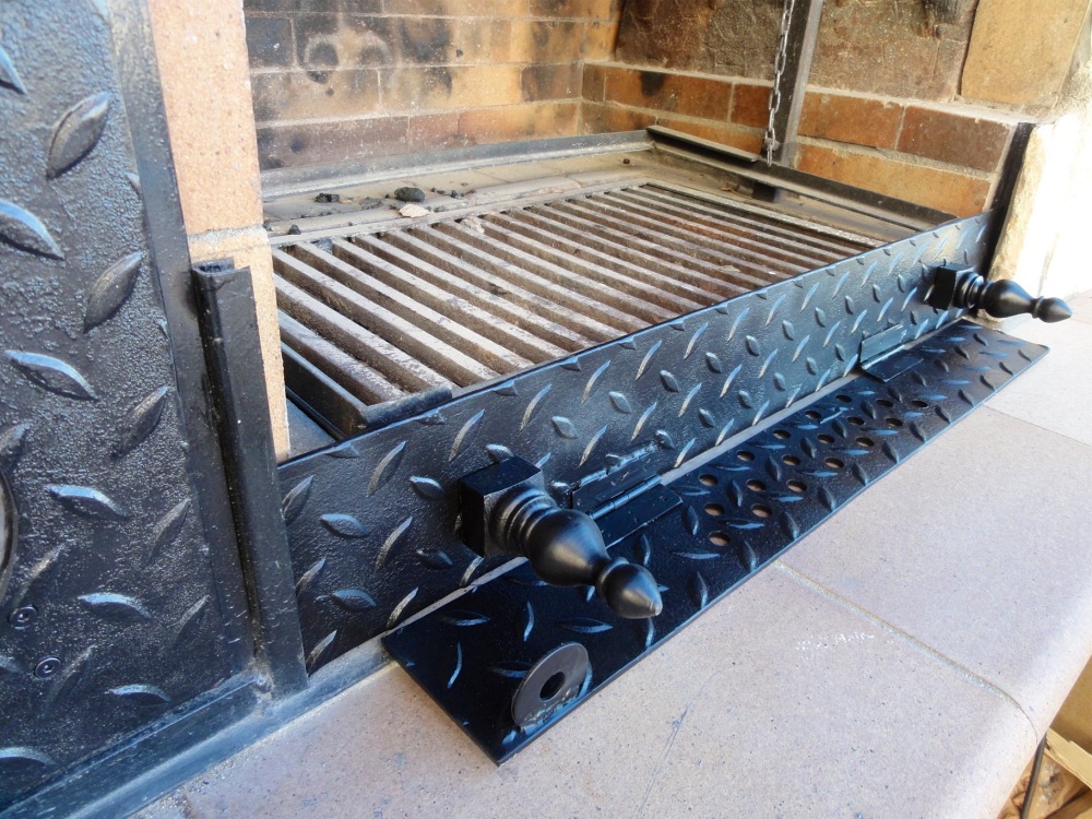 Wird die Klappe ganz abgesenkt, dann schließt sie oben mit dem Grillrost (hier auf dem Foto nicht eingeschoben) ab und die Glut darunter kann vom Wind nicht aufgewirbelt werden.  Mit einem Deckel überm Grillgut kann fast wie in einem Kugelgrill auch Ober- oder Rundumhitze erzeugt werden.