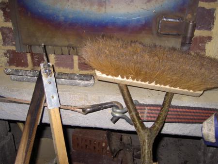 Mit dem Haken nehme ich den Stein aus dem Feuerraum und schließe das Ascheloch.