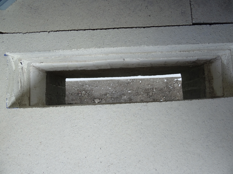 Blick durch den Ascheschacht nach unten, dort ist eine Schienensystem mit einem Behälter