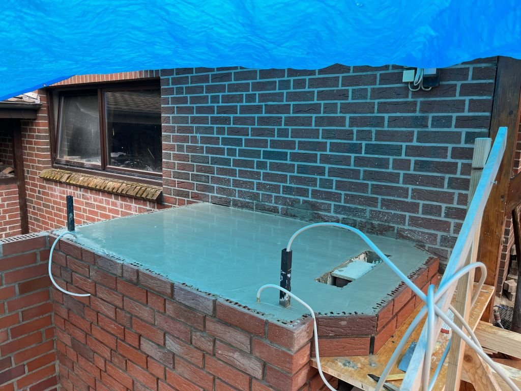 Bevor wir den  Beton gegossen haben, setzten wir in zwei Ecken noch 3x3 cm Kabelkanäle. Diese werden beim weiteren Mauern verlängert. Durch die Kanäle verlaufen nur jeweils zwei Kabel. Sie liegen in der Ecke der 16 cm starken Dämmung (+ 1 cm Luftschicht). Ich glaube nicht, dass da noch viel Wärme ankommt. Für den  Fall, dass doch etwas Wärme hineinkommt verläuft der Kanal durch den Beton und ist oben und unten offen. So kann warme Luft nach oben entweichen und kalte Luft von unten nachströmen.