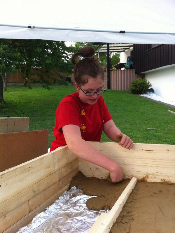 So, in die Bodenschalung kam dann eine Steinwolle-Isolierung, die ich mit Alufolie ab-<br />gedeckt habe. Inzwischen habe ich erfahren, dass Alufolie sinnlos ist, weil die recht schnell verrotten soll. Rundherum ein bisschen Platz gelassen (5 cm), damit man von aussen später die Isolierschicht nicht sieht. Auf dem Foto übrigens meine Tochter, die fleissig geholfen hat.